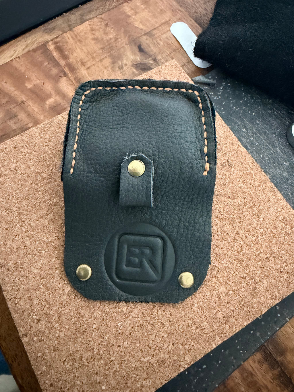 Achterkant van het leren AirPods hoesje met lus en gestempeld logo
